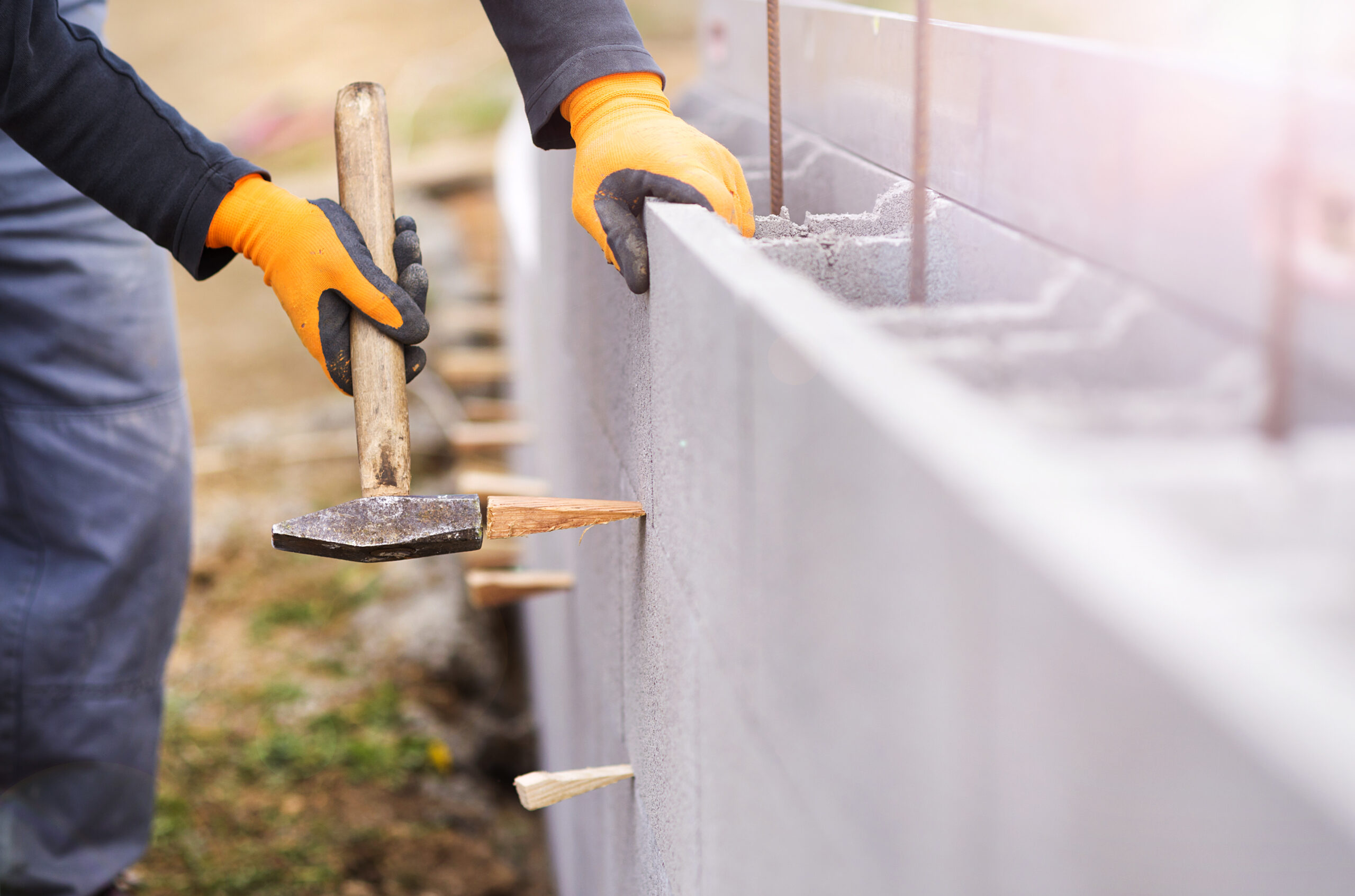bricklayer-putting-down-another-row-of-bricks-in-site-SBI-305162459-scaled